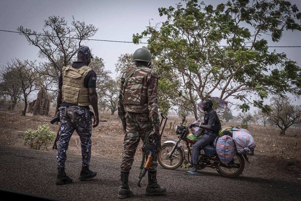 Un policier et un soldat béninois arrêtent un motocycliste à un poste de contrôle à l’extérieur de Porga, au Bénin, le 26 mars 2022. © Marco Simoncelli/AP/SIPA