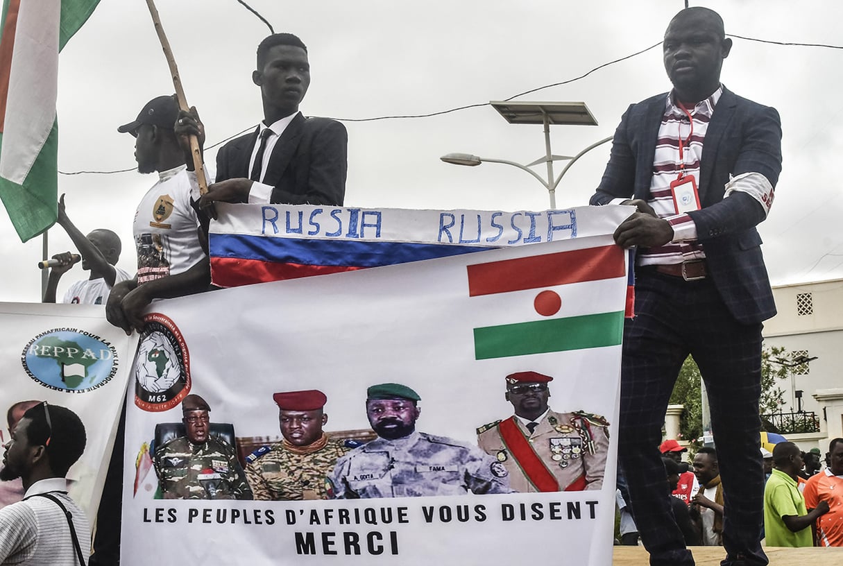 Des manifestants tiennent un drapeau russe et une banderole de soutien aux chefs des juntes du Niger, du Burkina Faso, du Mali et de la Guinée, lors de la fête de l’indépendance, à Niamey, le 3 août 2023.