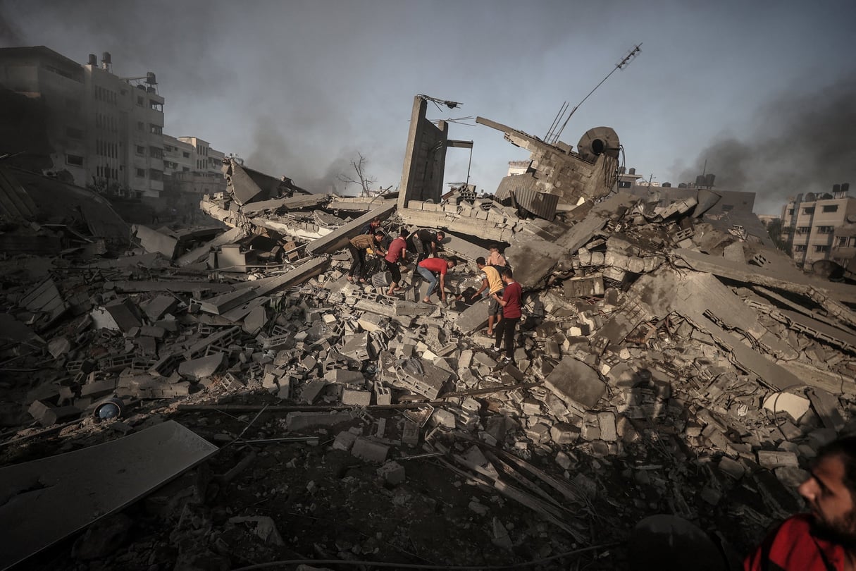 Des équipes de défense civile et des civils tentent de sauver des personnes sous les décombres après des attaques israéliennes et alors que les frappes aériennes et les tirs d’artillerie se poursuivent, à Gaza, le 25 octobre 2023. © Ali Jadallah/Anadolu via AFP