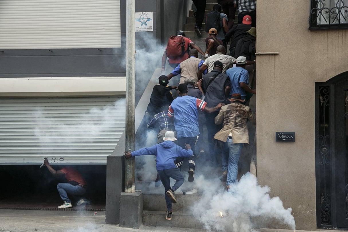 Des partisans de l’opposition courent se mettre à l’abri alors que des policiers anti-émeutes utilisent des gaz lacrymogènes pour les disperser à Antananarivo, le 2 octobre 2023. © RIJASOLO/AFP
