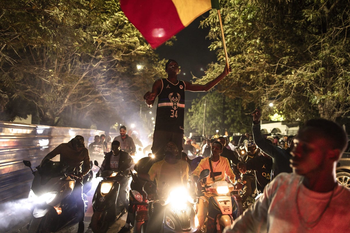 Des partisans de Bassirou Diomaye Faye, candidat de l’opposition à l’élection présidentielle, et d’Ousmane Sonko, chef de file de l’opposition, célèbrent le dépouillement des votes, à Dakar, au Sénégal, le 24 mars 2024. © Photo by JOHN WESSELS / AFP