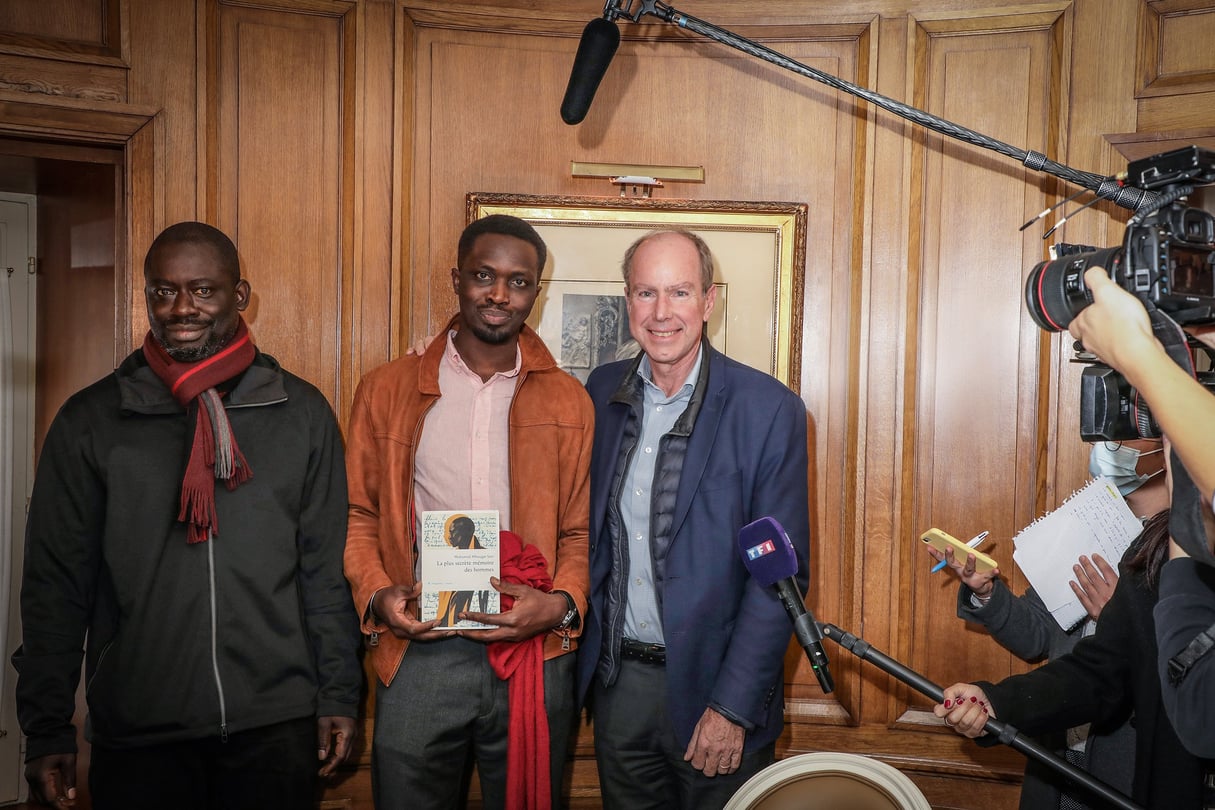Mohamed Mbougar Sarr (au centre), avec Felwine Sarr (à gauche) et Philippe Rey, lors de la remise du prix Goncourt, le 3 novembre 2021, au restaurant Drouan, à Paris. &copy; Olivier DION