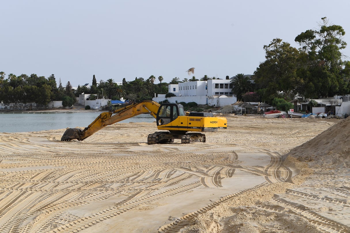 Une pelleteuse répand du sable prélevé dans des carrières du pays pour renflouer l’une des plages de la ville balnéaire de Hammamet, en Tunisie, le 28 juin 2024. © Photo by FETHI BELAID / AFP)