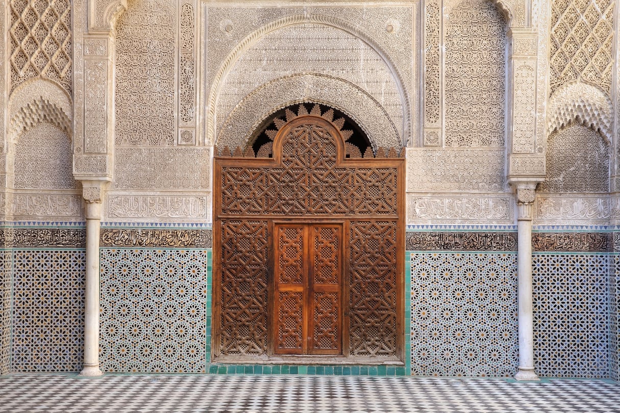 Porte en bois entourée de carreaux de zellige, dans une école religieuse de la médina de Fès, au Maroc. © Manuel Cohen / Aurimages