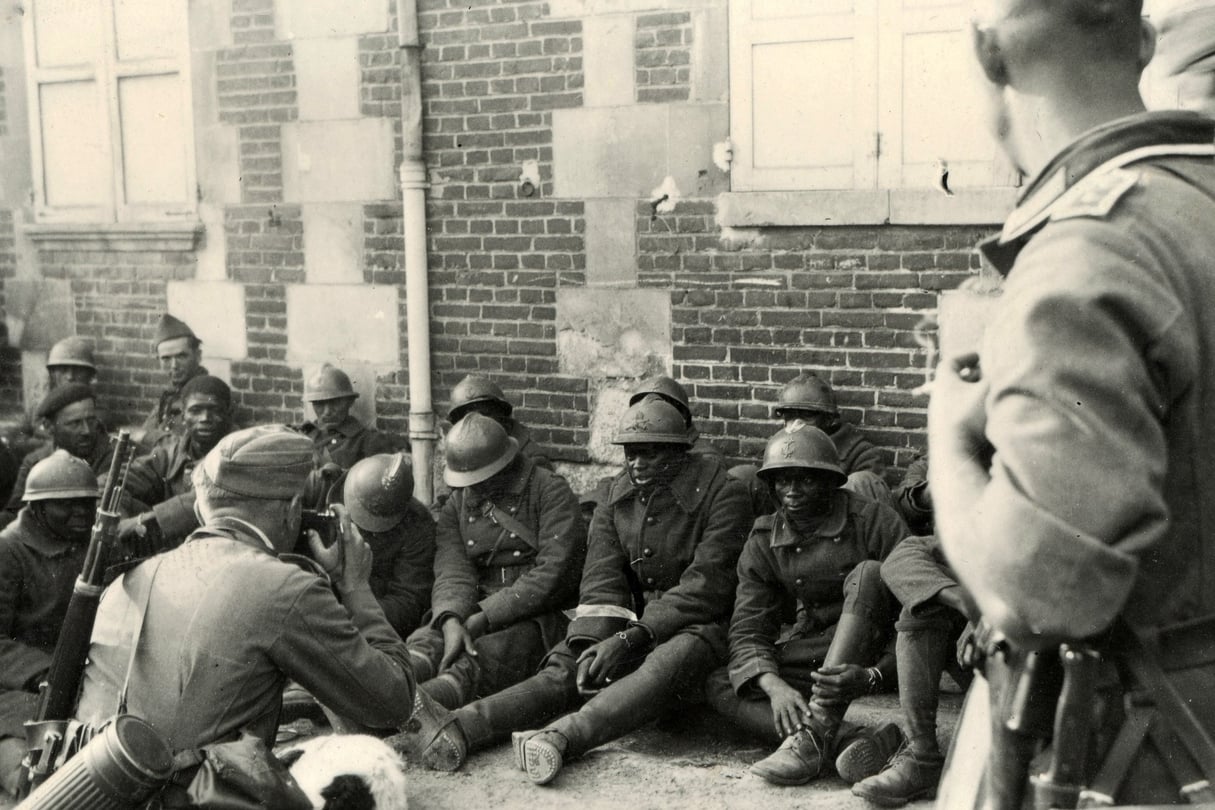 Soldat allemand photographiant des tirailleurs sénégalais venant d’être faits prisonniers, en France, en juin 1940. © Coll. Boursaux/adoc-photos