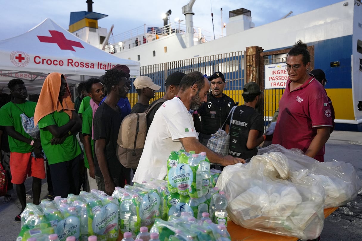 Équipes de la Croix-Rouge italienne distribuant des bouteilles d’eau et des vivres à des migrants, sur l’île de Lampedusa, le 18 septembre 2023. © Zakaria Abdelkafi/AFP