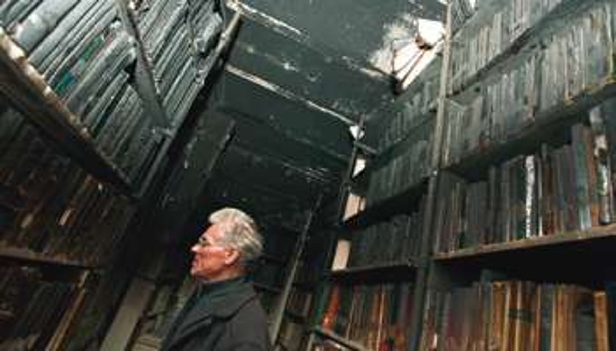 Le père Jean Fontaine au milieu des décombres calcinés de la réserve de livres © Ons Abid pour J.A