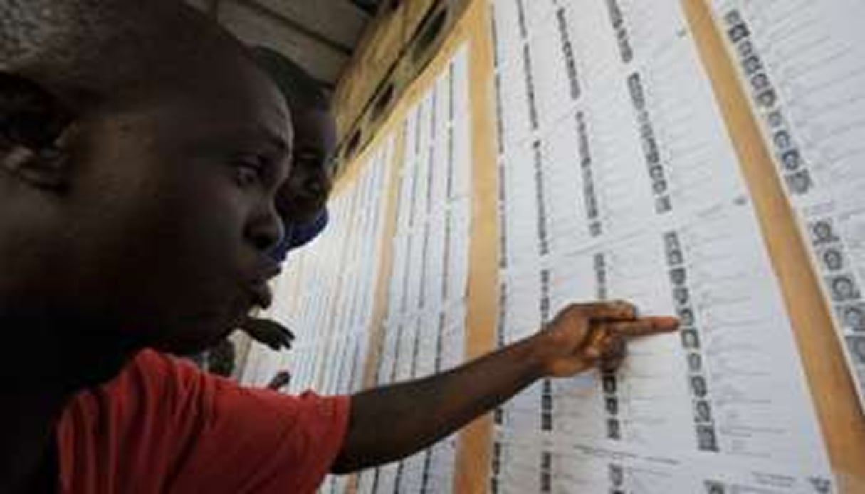 Des habitants d’Abidjan cherchent leur nom sur la liste électorale provisoire © AFP