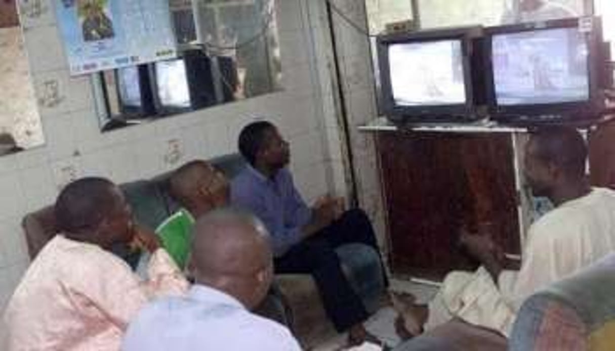 Des habitants de Lagos regardent la télévision dans la boutique d’un barbier, en novembre 2002. © AFP