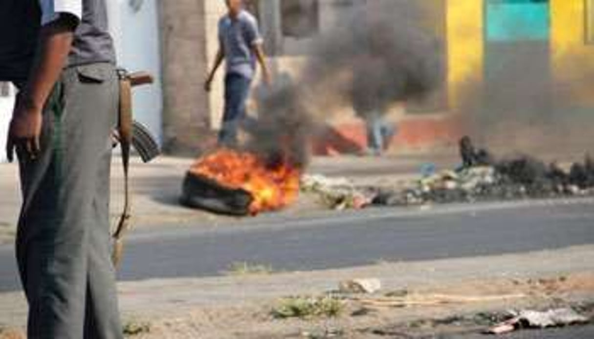 Un policier près d’un pneu incendié dans les rues de Maputo, le 2 septembre 2010 au Mozambique. © AFP