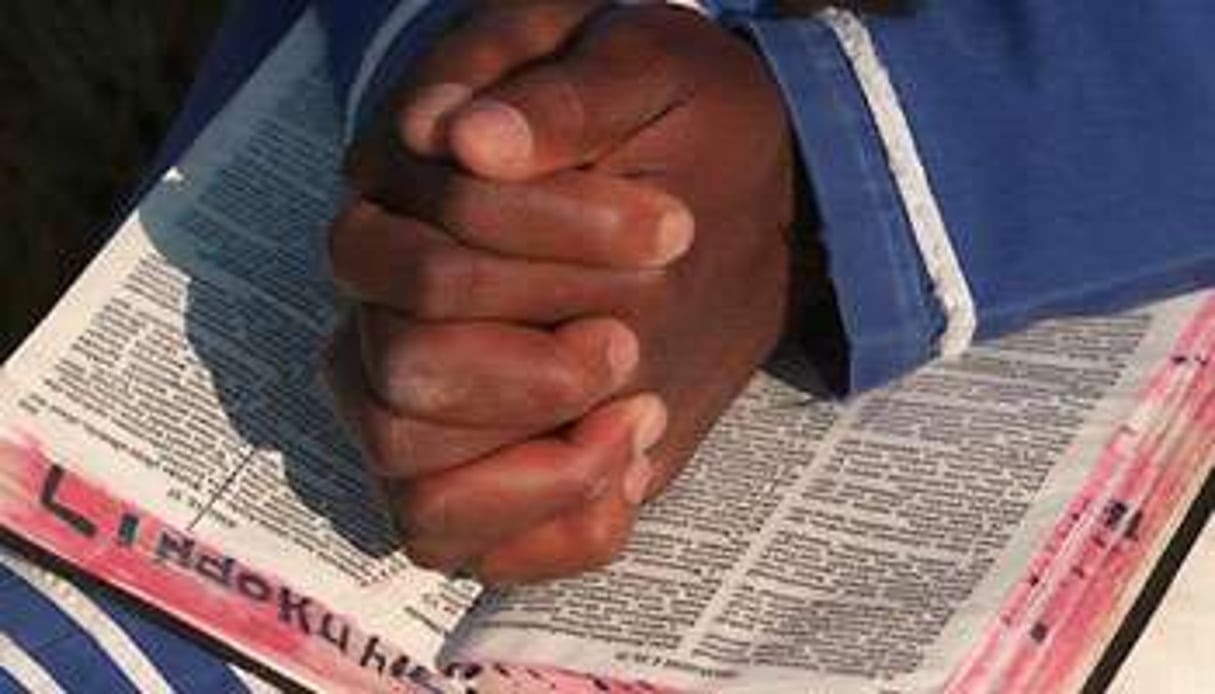 Un enfant prie, une bible sur les genoux, près de Johannesbourg, en Afrique du Sud. © AFP