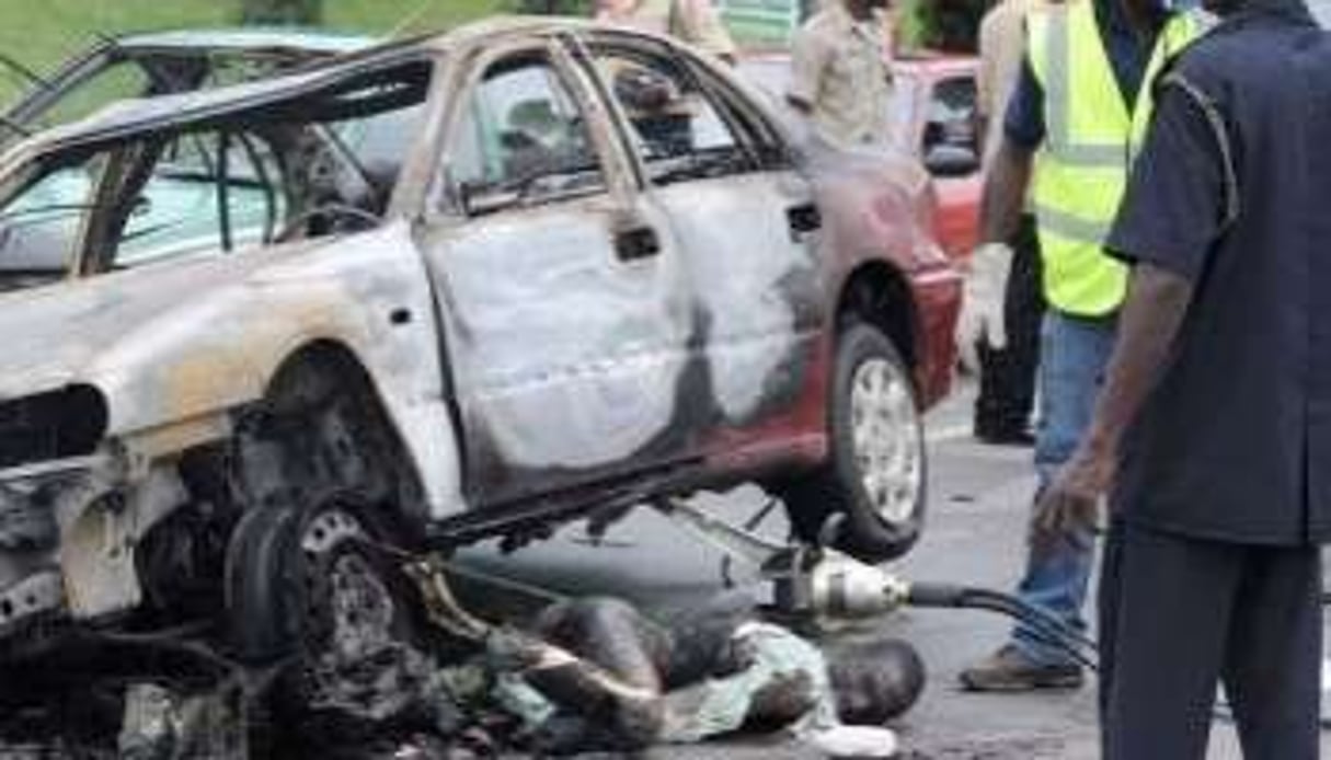 Des agents de sécurité inspectent une voiture ayant explosé à Abuja, le 1er octobre 2010. © AFP
