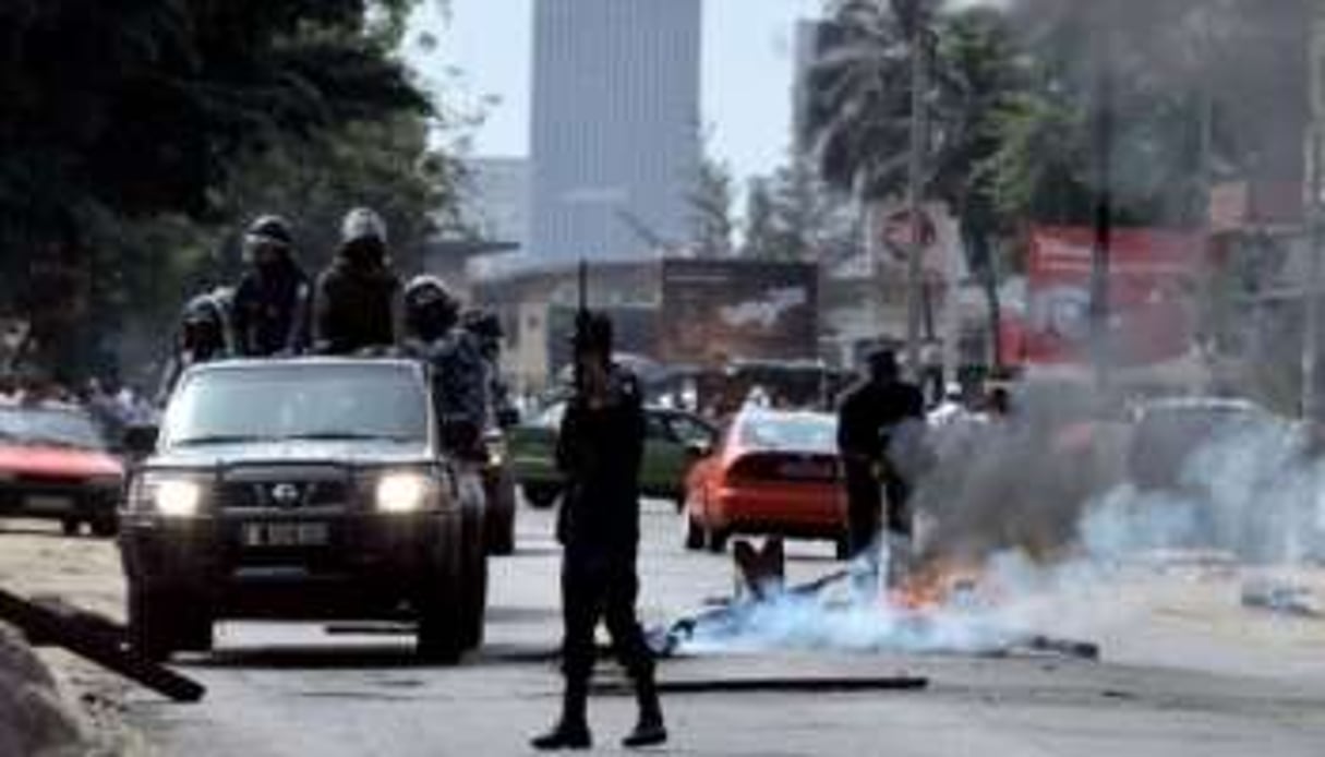 Des gendarmes ivoiriens éteignent un feu de pneus à Abidjan le 6 décembre 2010. © AFP