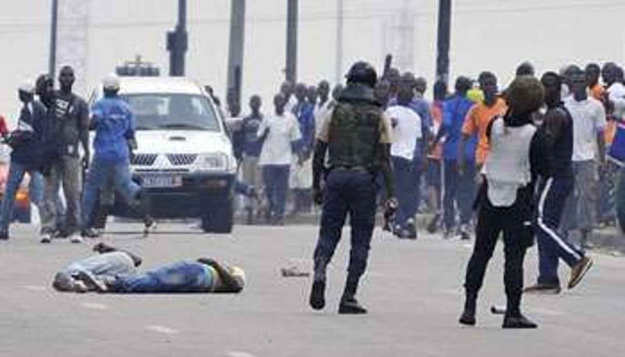 Deux blessés à terre à Abidjan, le 16 décembre, après la dispersion d’un rassemblement. © AFP