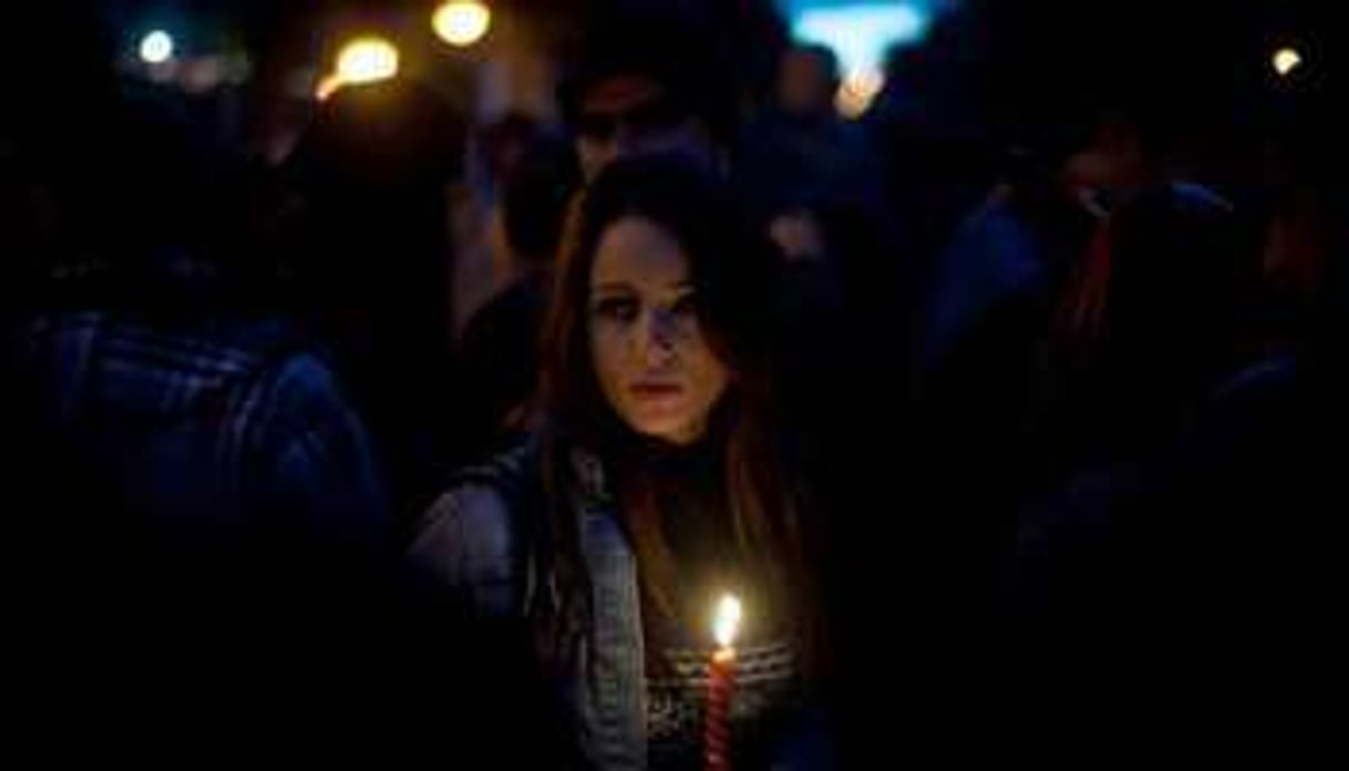 Une jeune femme tient une bougie lors d’une manifestation à Tunis, le 22 janvier. © AFP