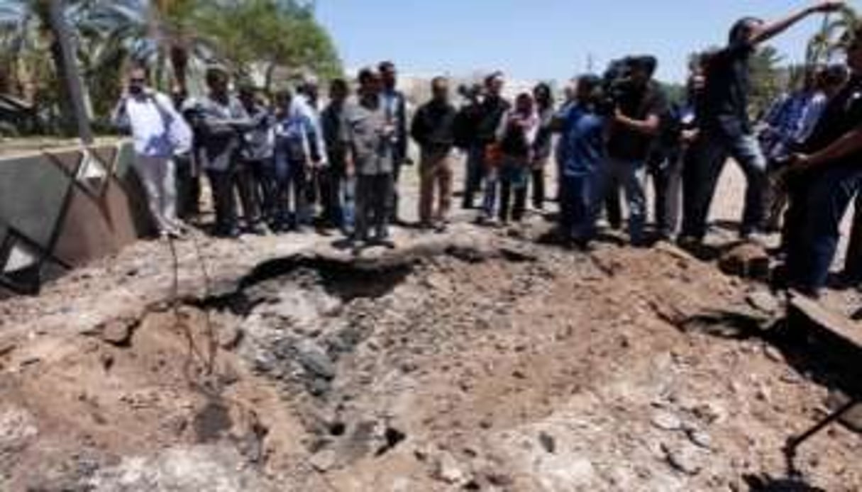 Journalistes devant un cratère de bombardement, à Tripoli, le 11 mai 2011. © AFP