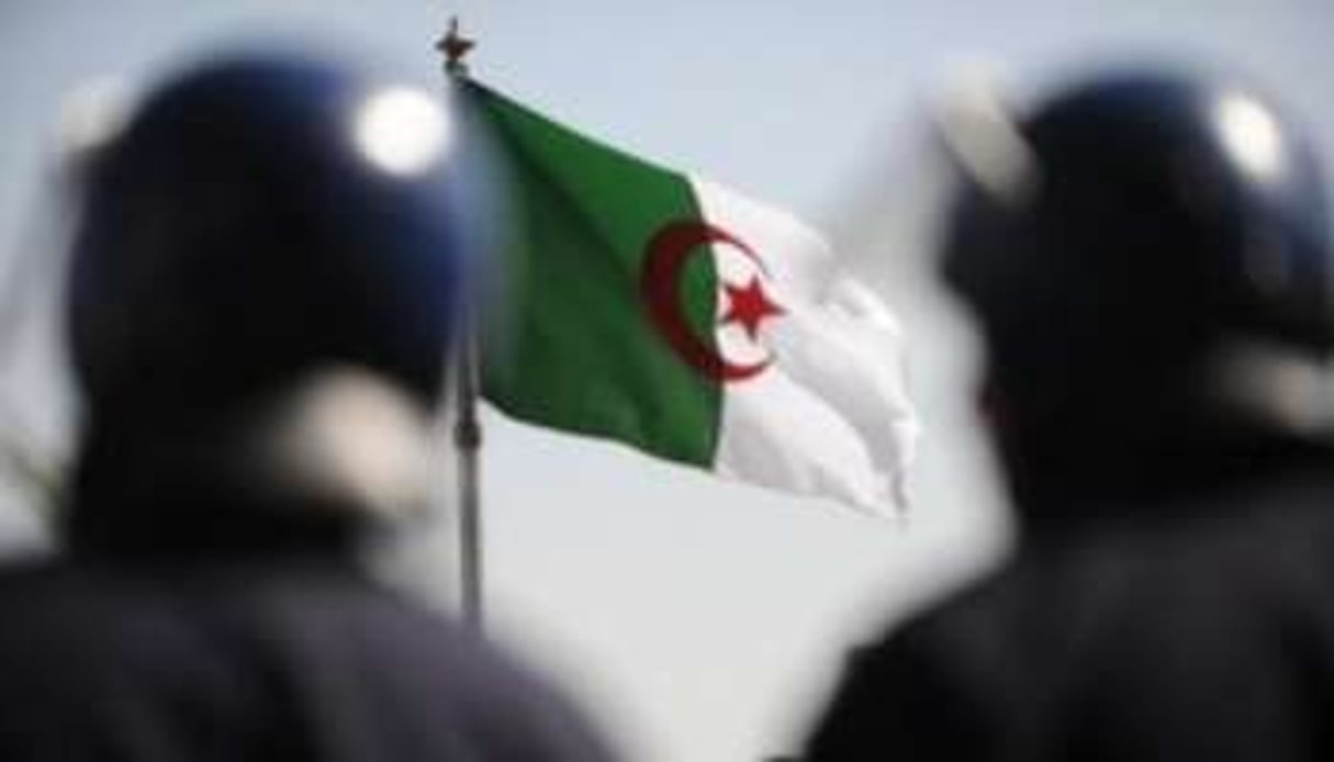 Deux policiers devant le drapeau algérien © Farouk Batiche/AFP/Archives