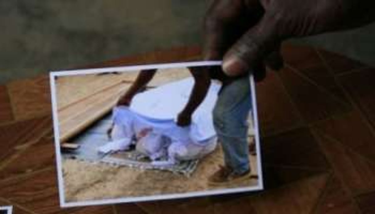 Un immigrant au Gabon, le 18 juin 2011, montre une photo représentant selon lui l’une des victimes. © AFP