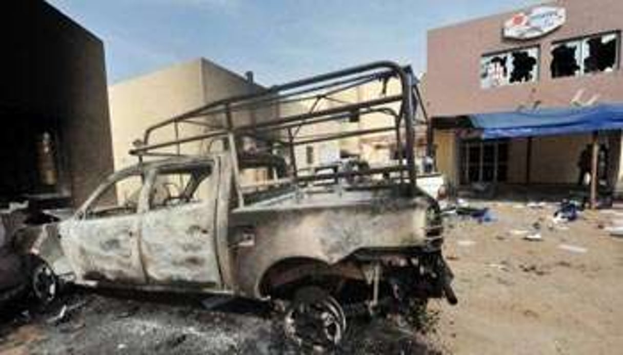 L’épave d’un véhicule incendié devant l’enseigne de la Senelec, le 28 juin. © AFP