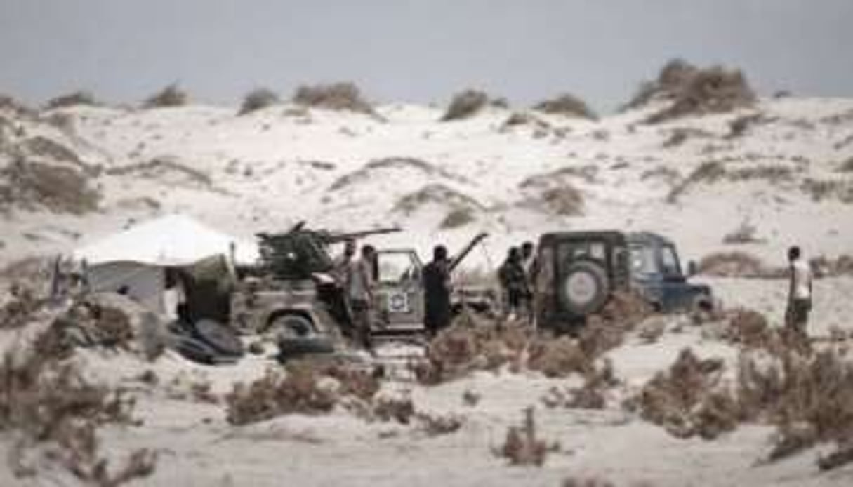 Des combattants rebelles libyens entre les dunes de sable, aux abords de la ville de Brega, le 10 ao © AFP