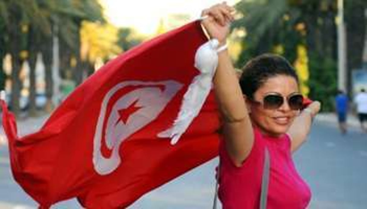 Une Tunisienne porte le drapeau national. © AFP