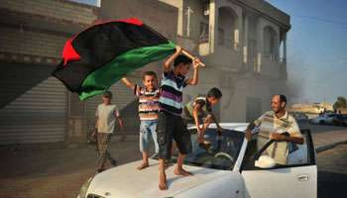 Des enfants avec le drapeau de la rebellion à Al-Jamil, dans l’ouest de la Libye, le 27 août 2011. © AFP