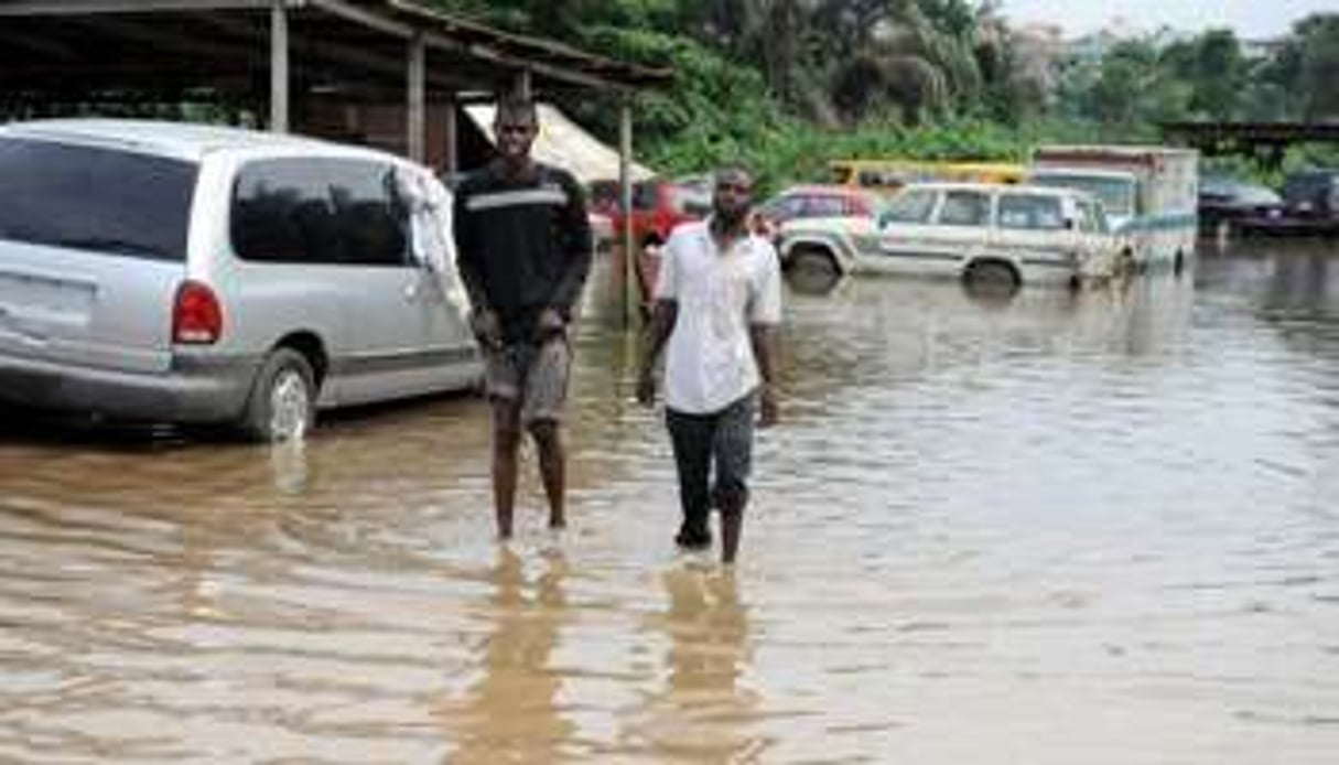 Deux hommes sur une route inondée à Lagos le 11 juillet 2011. © AFP