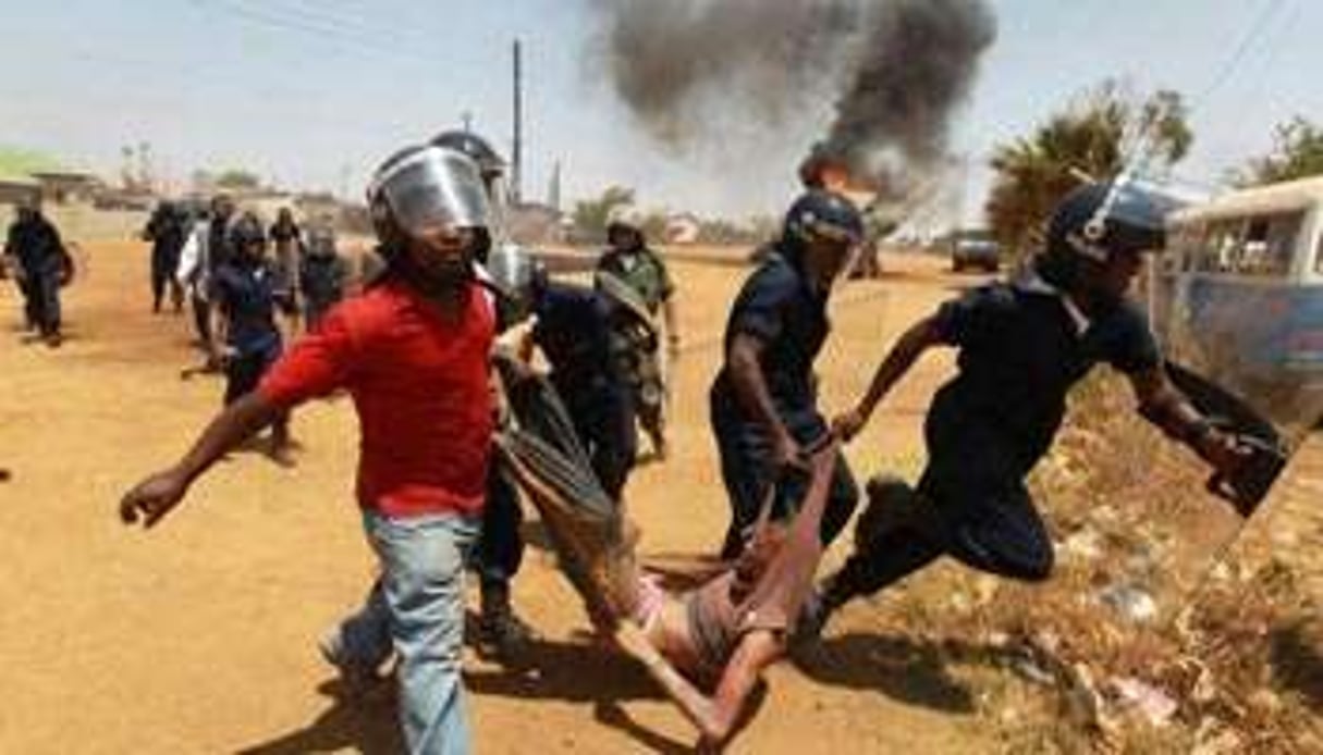 Un suspect emmené par la police lors d’émeutes dans un bidonville de Lusaka, en Zambie. © AFP