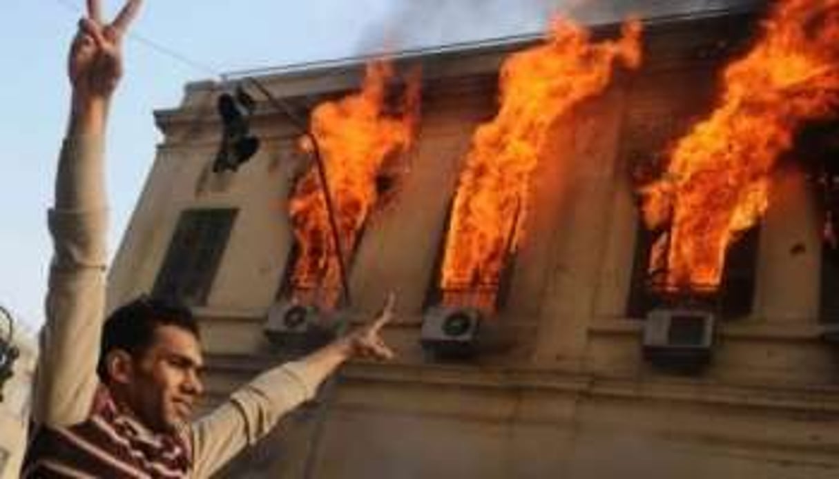 Un manifestant dans les rues du Caire près d’un bâtiment en flammes le 17 décembre 2011. © AFP