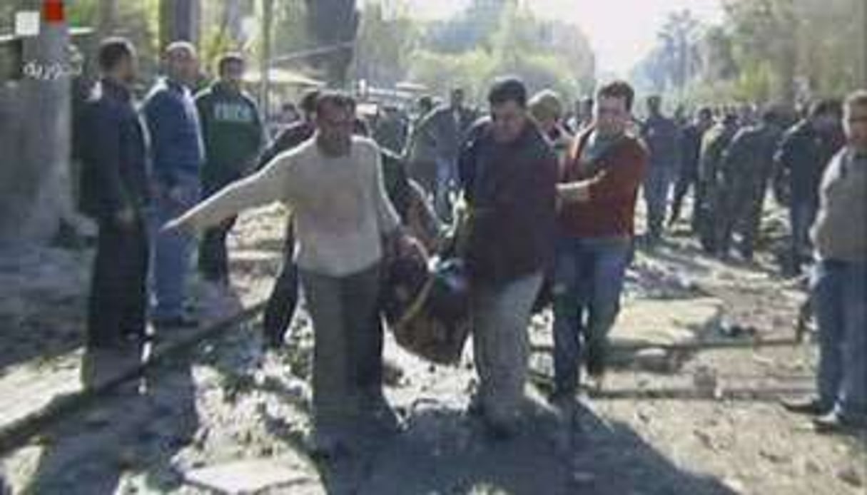 Des hommes évacuant les corps des victimes d’un attentat suicide, le 23 décembre 2011 à Damas. © Syrian TV/AFP