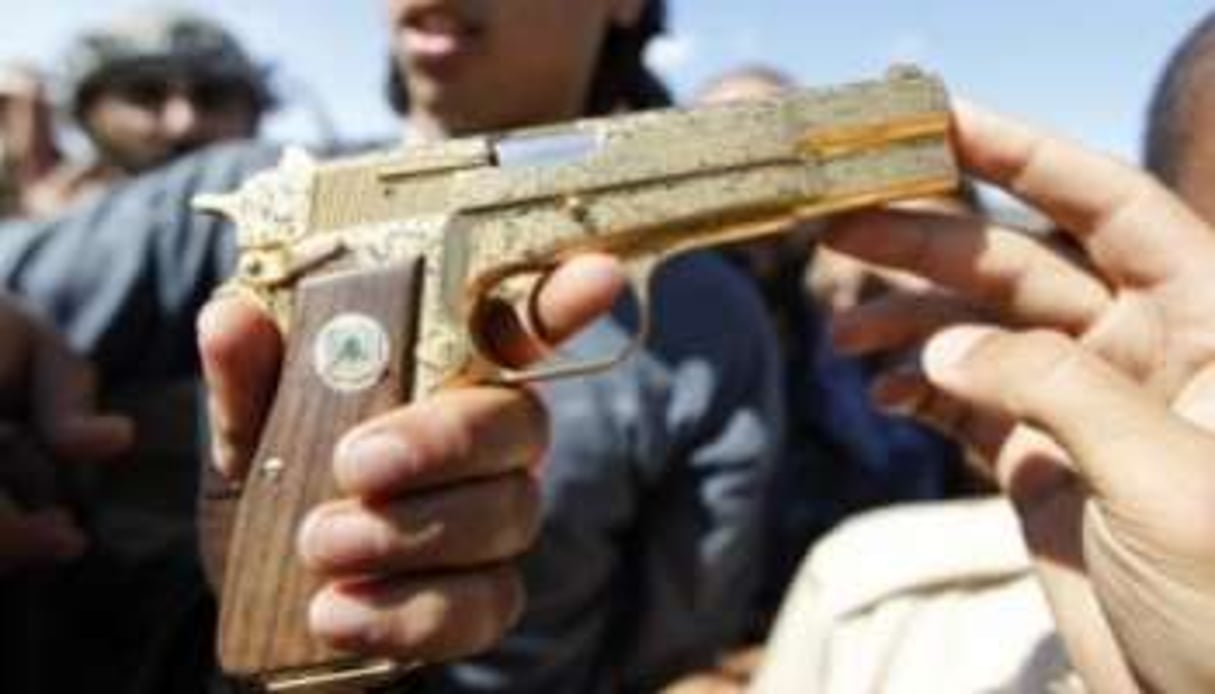 Le 20 octobre 2011 près de Syrte, un jeune rebelle exhibe le Parabellum 9 mm plaqué or de Kaddafi. © Thaier al-Soudan/Reuters