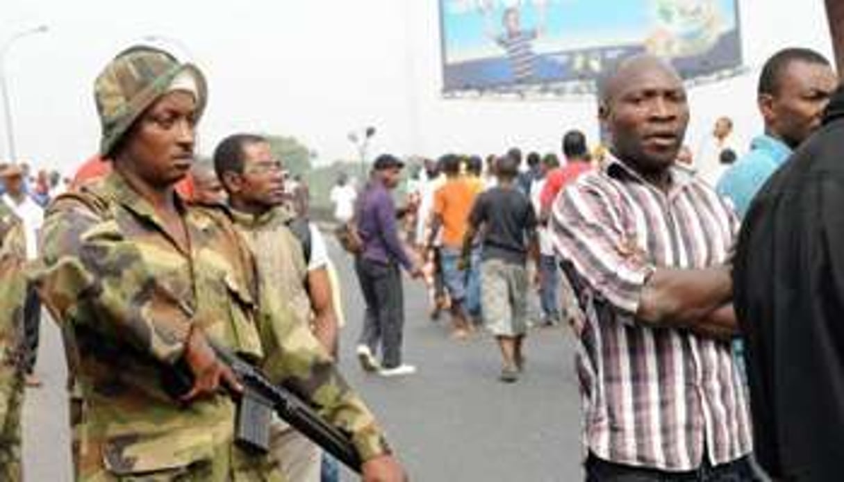 Un soldat nigérian se tient à côté de manifestants à Lagos le 16 janvier 2012. © AFP