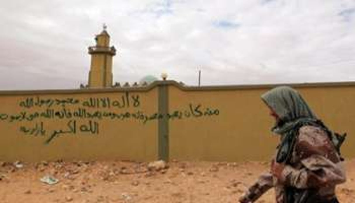 Un membre du CNT libyen passe devant des graffitis anti-Kaddafi à Bani Walid, en octobre 2011. © AFP