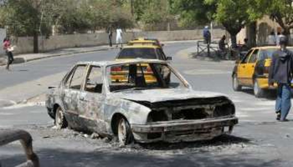 Une voiture brûlée après les heurts du samedi 28 janvier 2012 à Dakar, au Sénégal. © Seyllou/AFP