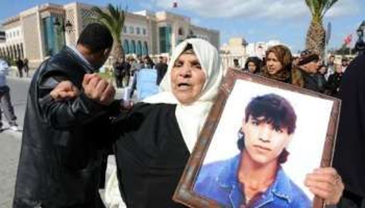 Une femme tient le portrait de son fils mort lors de la révolution, le 27 février 2012 à Tunis. © AFP