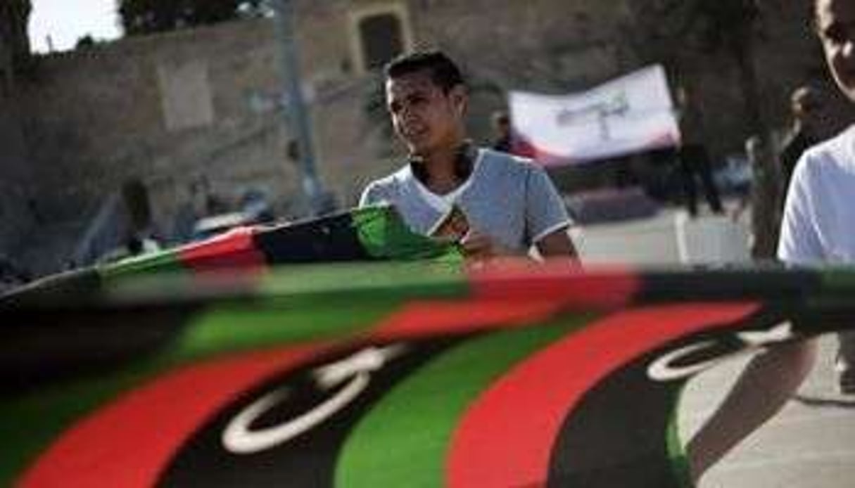 Un jeune homme devant le drapeau libyen pendant une manifestation, à Tripoli. © AFP