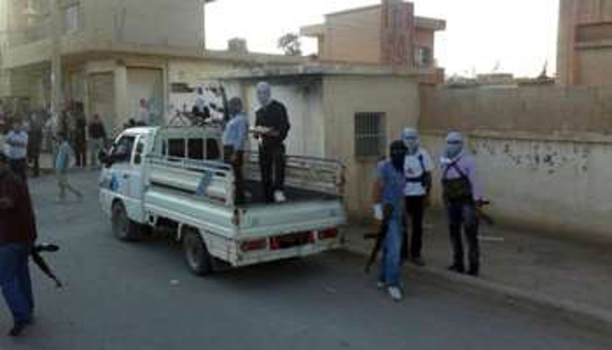 Des rebelles cagoulés dans une rue de Saqba, dans la banlieue de Damas. © AFP