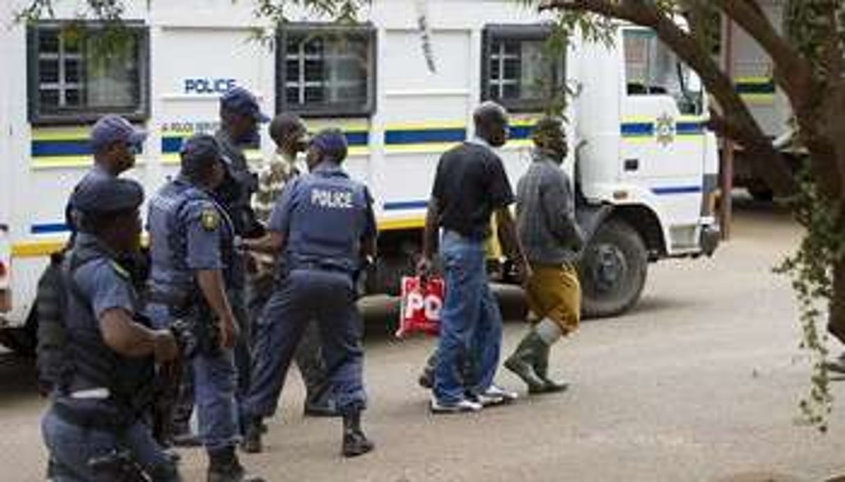 Des mineurs de Marikana accusés d’actes de violence sont escortés par des policiers. © AFP