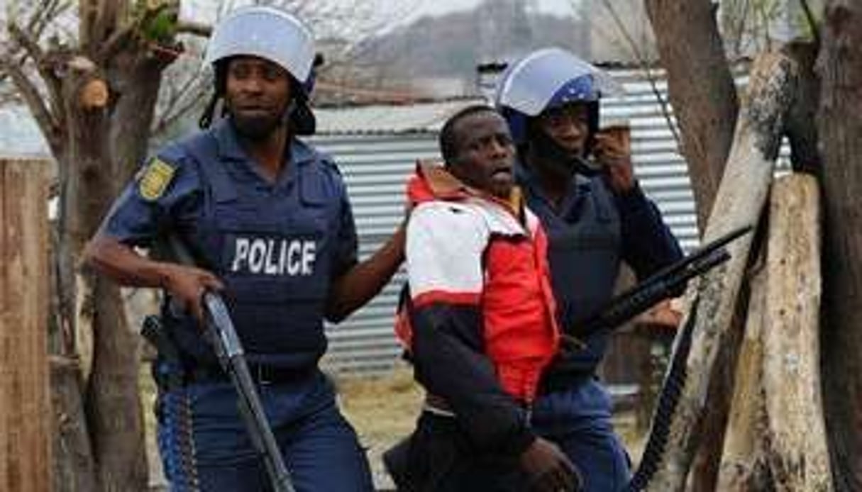 Des policiers sud-africains arrêtent un mineur à Marikana, le 15 septembre 2012. © AFP