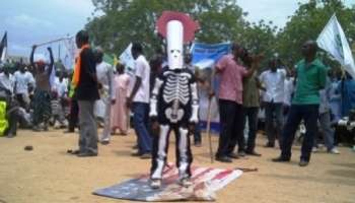 Un manifestant revêtu d’un costume de squelette, piétine un drapeau américain le 22 septembre. © Aminu Abuabakar/AFP