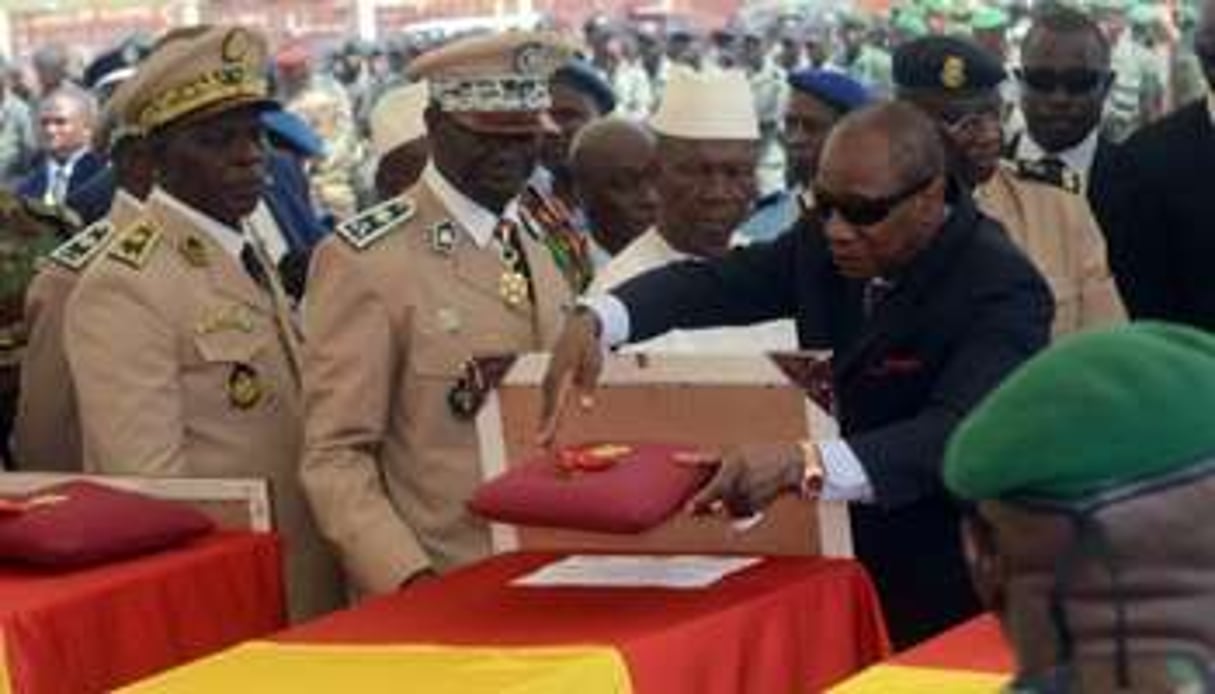 Le président guinéen Alpha Condé (d) devant les cercueilsdes victimes d’un crash d’avion au Liber © AFP