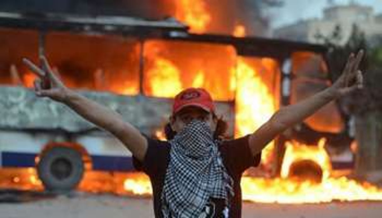 Un manifestant devant un bus des Frères musulmans incendié, au Caire, le 22 mars 2013 © AFP