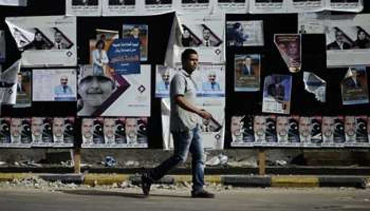 Un homme passe devant un mur couvert d’affiches politiques le 5 juillet 2012 à Tripoli. © AFP