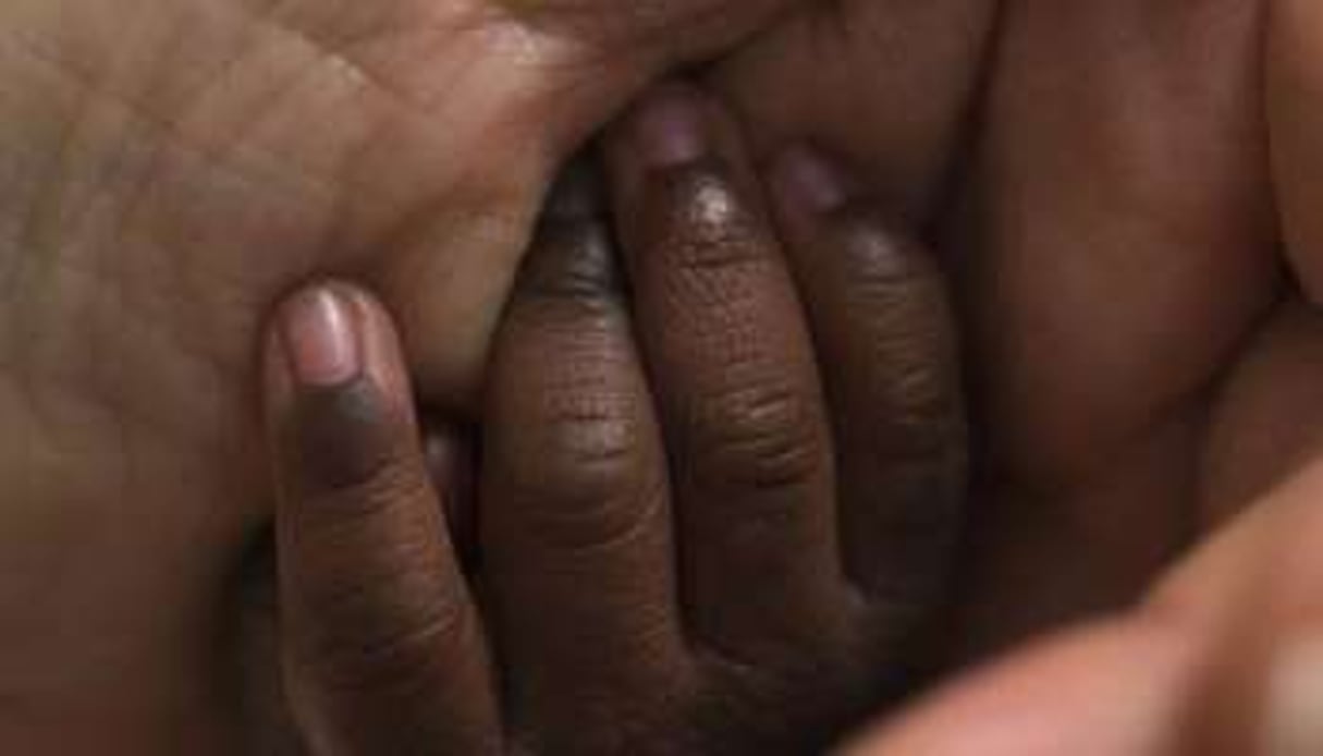 Une femme tient la main d’un bébé. © Joel Saget/AFP
