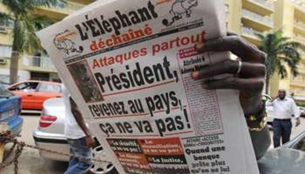 Un homme lit un exemplaire du journal satirique l’Eléphant déchaîné, dans une rue d’Abidjan. © AFP