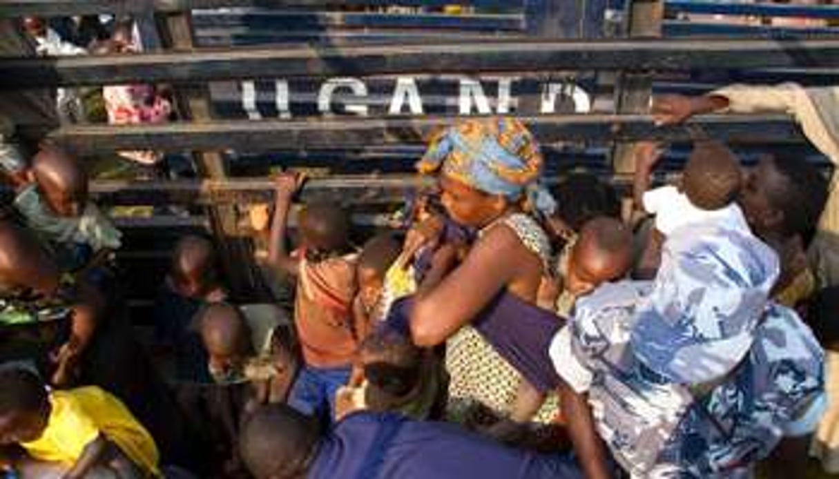 Des policiers ougandais transportent des femmes et des enfants congolais vers Bubukwanga. © AFP