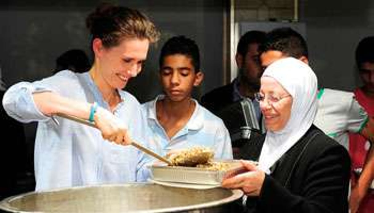 Asma al-Assad, à gauche, dans un orphelinat de Damas, le 4 août. © AFP