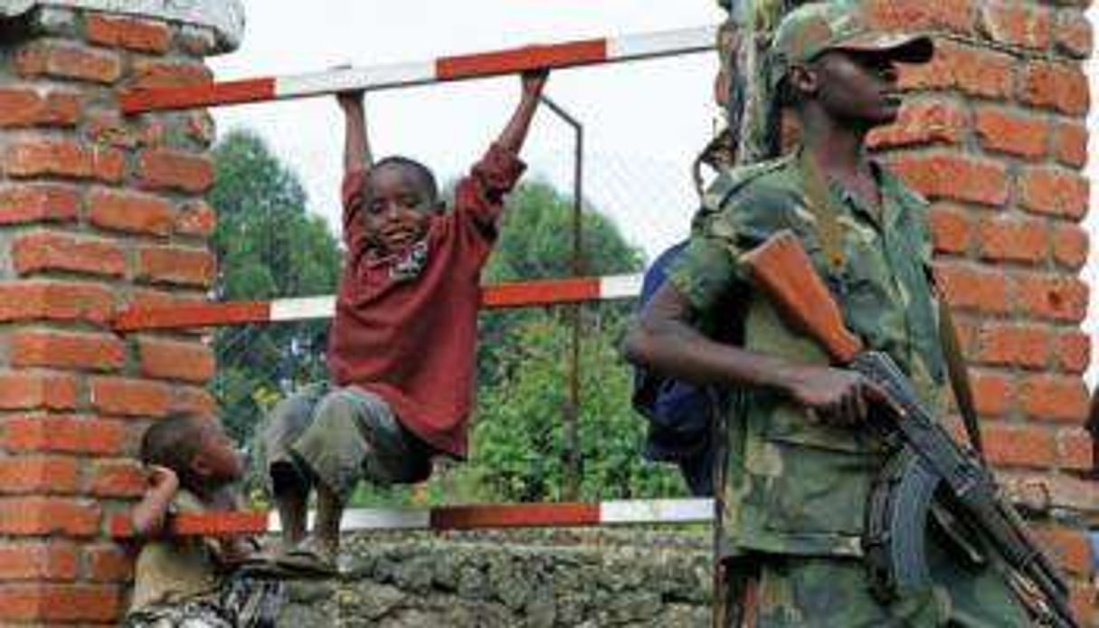 Des enfants jouent près d’un soldat rebelle du M23 le 7 mars 2013 à Bunagana. © AFP