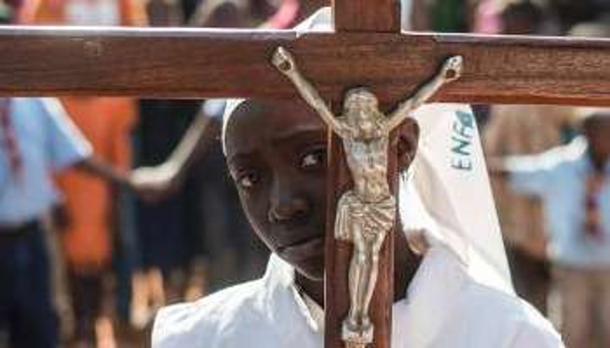 Une jeune fille portant une croix arrive à l’église Saint-Charles Lwanga,. © AFP