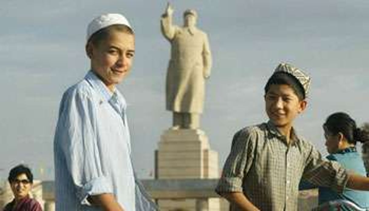 De jeunes Ouïgours devant la statue de Mao Zedong. © FREDERIC BROWN / AFP